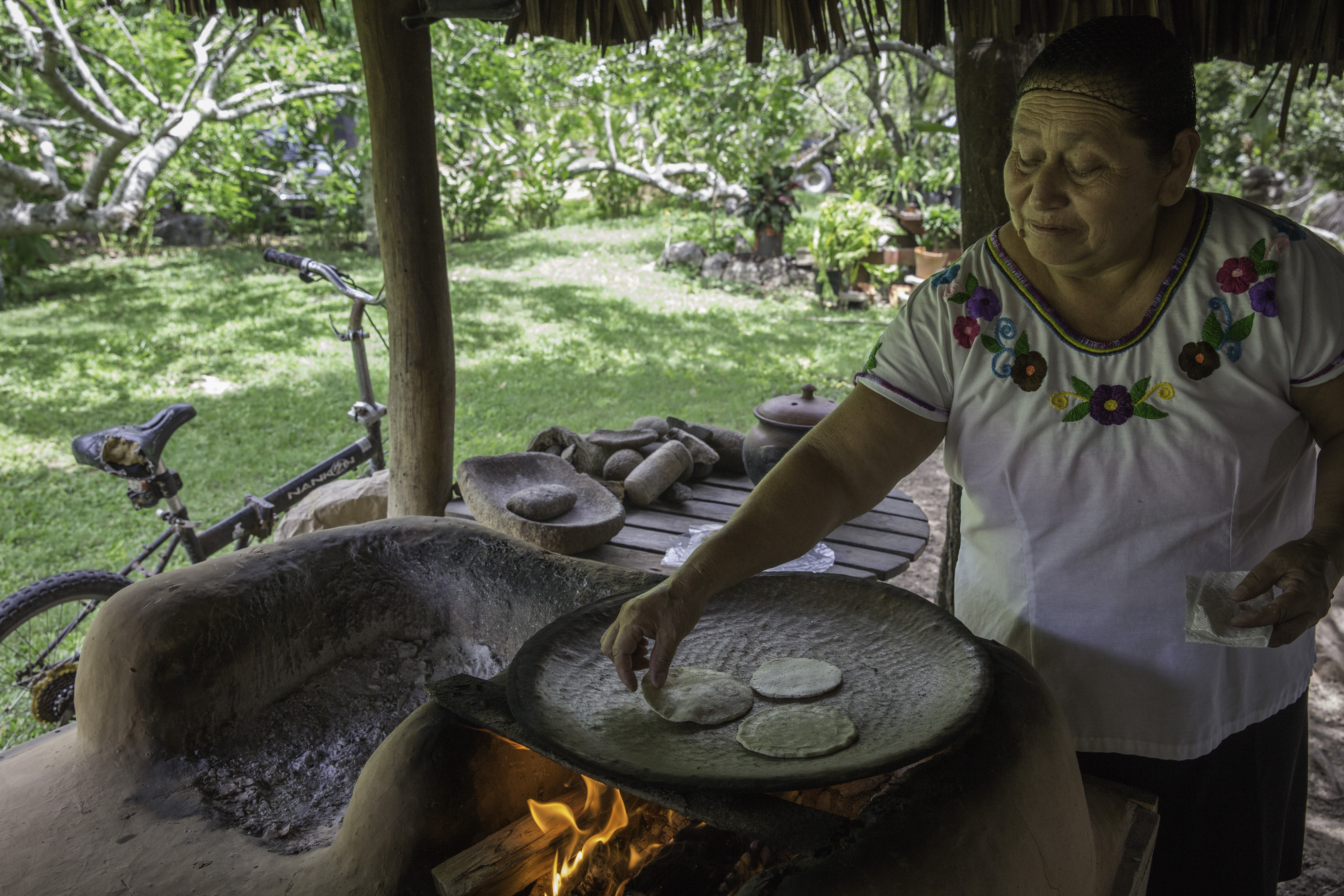 A woman makes tortillas over an open stove